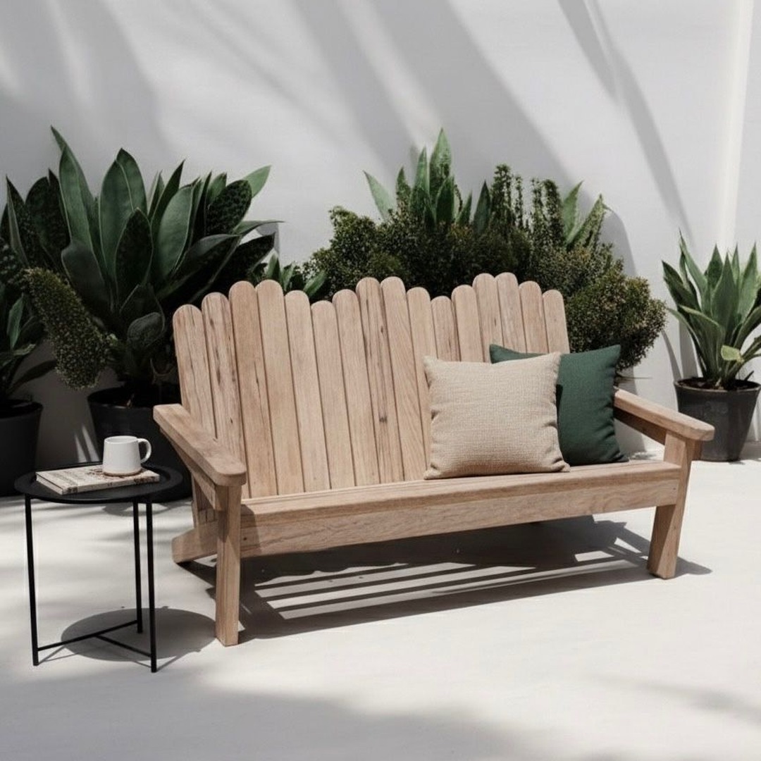 Long wooden Adirondack bench with a curved backrest and decorative pillows